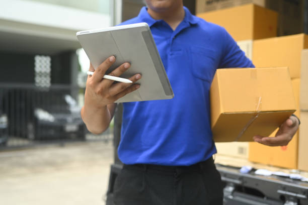istock Delivery worker holding a cardboard box and using digital tablet. E-commerce, shipping and delivery services concept 2170134395