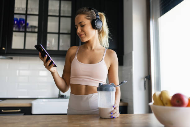 istock Sportswoman drinking smoothie and using phone in the kitchen 2170135504