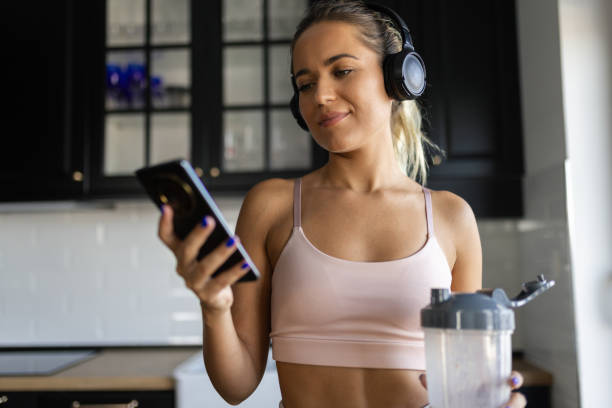 istock Sportswoman drinking smoothie and using phone in the kitchen 2170135526