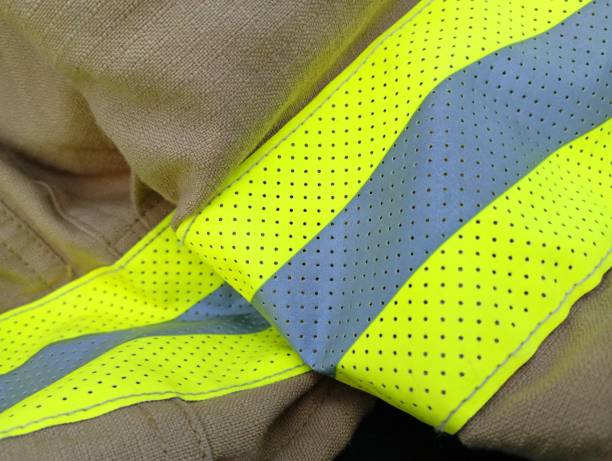 istock Fireman's brown combat clothing with reflective yellow lines on a brown background. Fabric background with reflective tapes. 2170135991