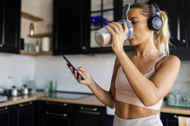 istock Sportswoman drinking smoothie and using phone in the kitchen 2170136279