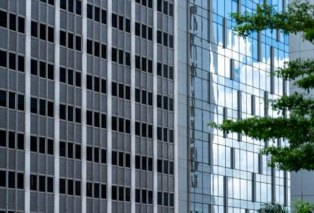 Two buildings with contrasting window patterns stand side-by-side. The one on the left has small, square windows in a grid pattern, while the one on the right has larger, rectangular windows with a modern, sleek design. dos edificios con patrones de ventanas contrastantes se encuentran uno al lado del otro. el de la izquierda tiene ventanas pequeñas y cuadradas en un patrón de cuadrícula, mientras que el de la derecha tiene ventanas rectangulares más grandes con un di