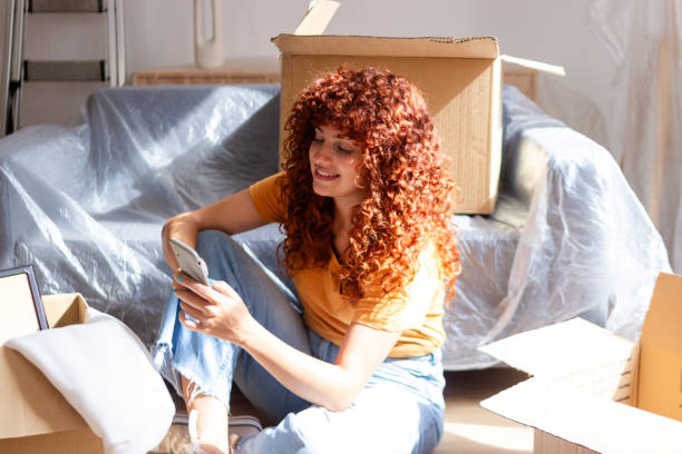 istock Young woman is taking a break from unpacking and is using her smartphone 2170144817
