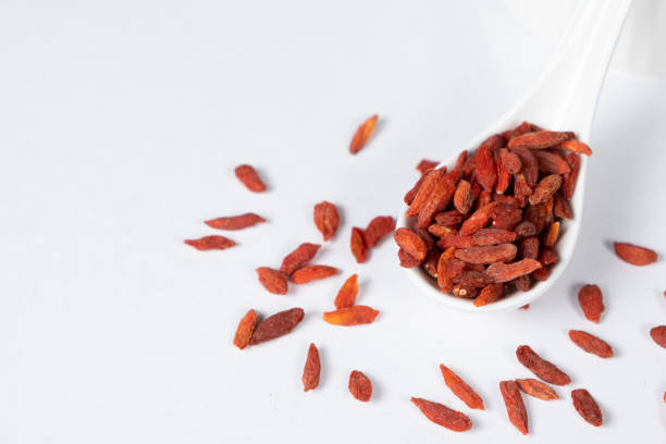 Dried Goji berries Lycium barbarum in a spoon on a white background.