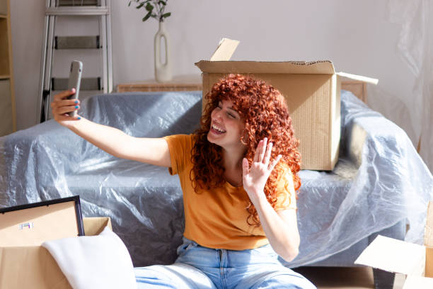 istock Woman taking selfie while video calling surrounded by moving boxes 2170145172