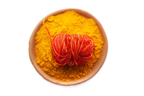 An earthen pot filled with Turmeric (Haldi) with kalawa (pooja thread). Isolated on a white background.
