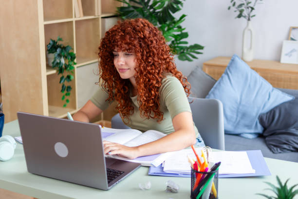 istock Young woman studying online at home using laptop computer 2170146035