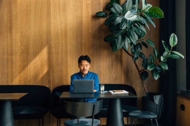 uomo che lavora sul laptop in uno spazio di lavoro moderno e minimalista - moderno immagine foto e immagini stock