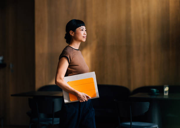 Confident Woman Holding Notebook in Modern Office Environment
