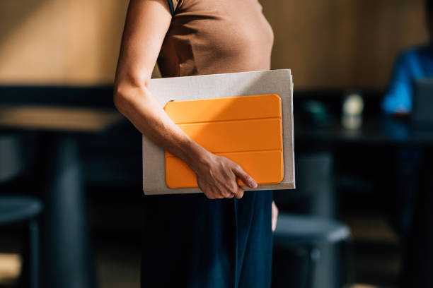 istock Woman Holding Orange Tablet in a Modern Workspace 2170146486