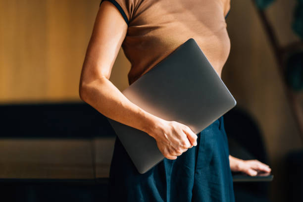 A professional woman confidently holds a laptop in a stylish office environment, symbolizing professionalism, technology, and success in the business world.