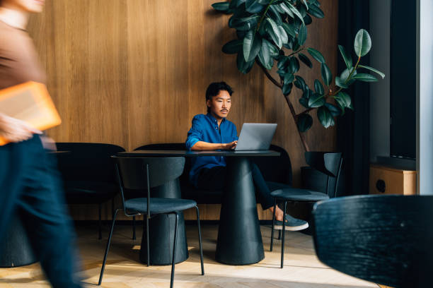 istock Man Working on Laptop in Modern Cafe with Wooden Interior 2170146500