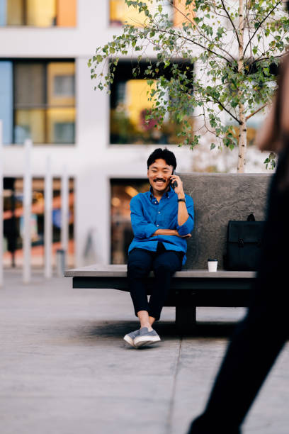 istock Happy Man Talking on Phone While Relaxing on Outdoor Bench 2170146509