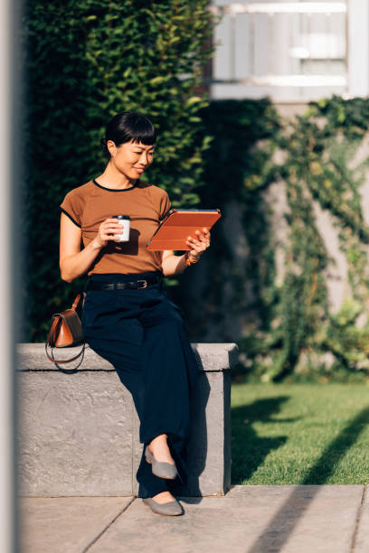 Woman Relaxing Outdoors With Tablet and Coffee in Sunlight