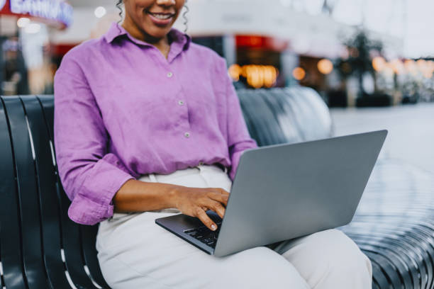 istock Woman Sitting on Bench Using Laptop in Shopping Mall 2170146628