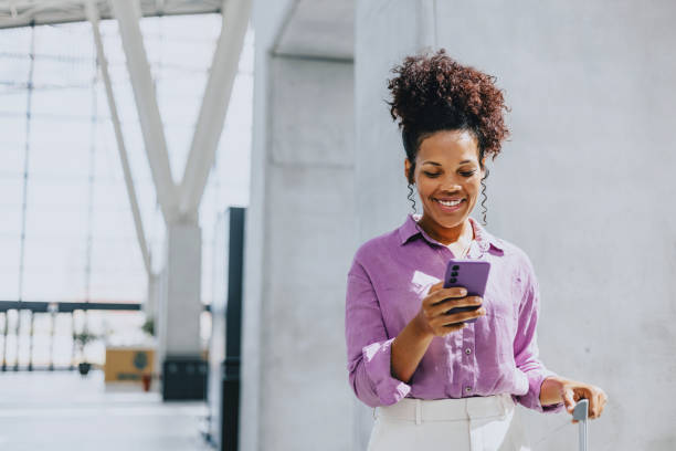istock Smiling Woman Using Smartphone in Modern Airport Terminal 2170146629