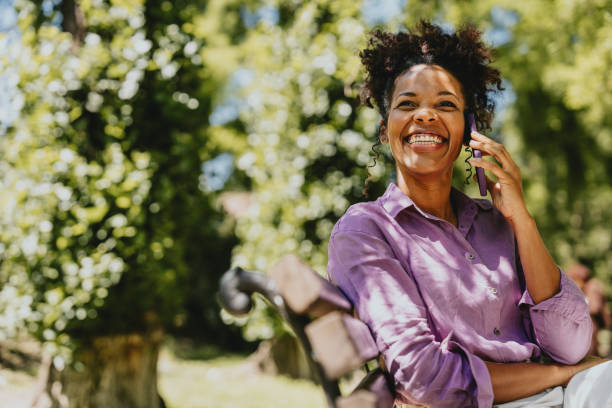istock Joyful Woman Talking On Phone In Sunny Park Setting 2170146664