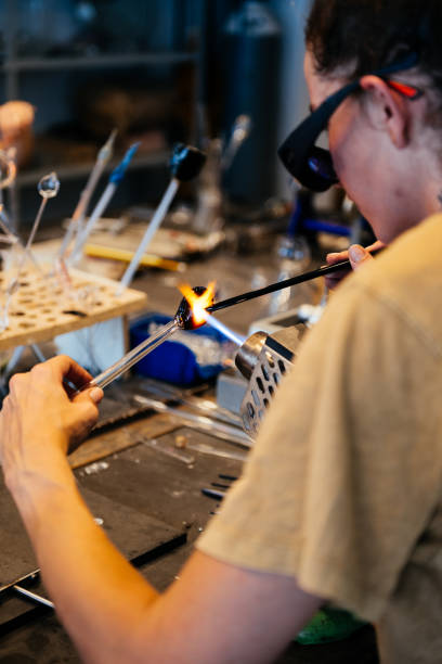 istock Young Female Glassblower Heating Glass Rod With Torch in Workshop 2170151439