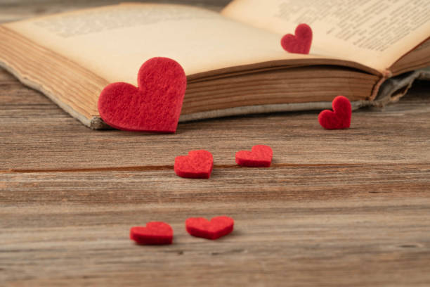 istock old opened book and red hearts on wooden background 2170153277
