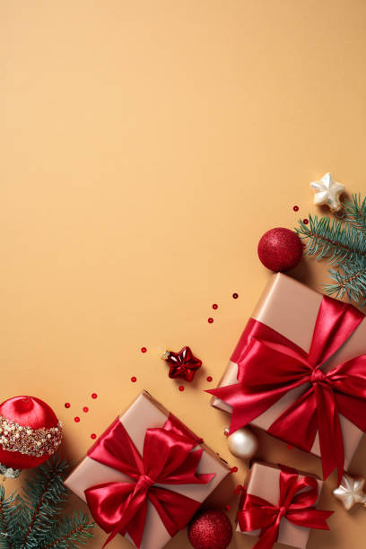 istock Christmas vertical background with luxury gift boxes with red ribbon, red baubles, fir branches, ornaments on beige. 2170153540
