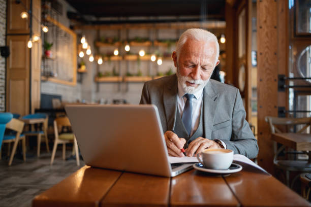 istock Elderly man working on laptop with documents in cafe 2170156063