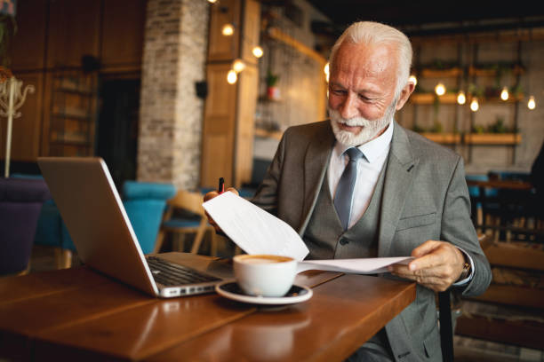 istock Senior man going through papers cheerfully in cafe 2170156173