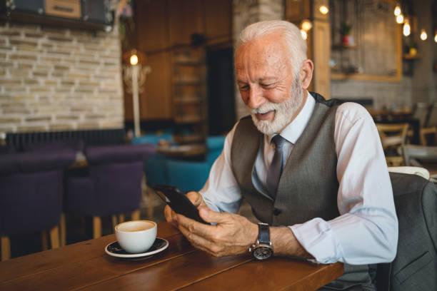istock Elderly man in grey suit engages with smartphone in cafe 2170156325