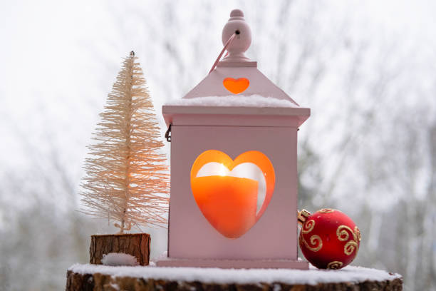 Soft white snow gracefully descends onto charming scene, featuring romantic candle lantern, Christmas tree, Christmas atmosphere and festive mood