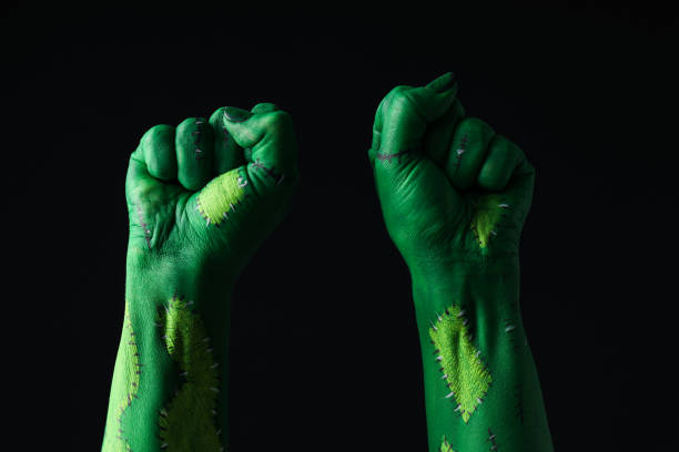 Green hands clenched into fists on black background, close up