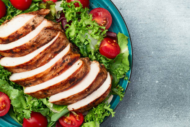istock Grilled chicken breast ( fillet ) with lattuce salad and cherry tomatoes . Top view 2170170301
