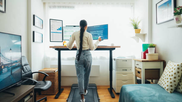 istock Woman working at standing desk is using credit card while walking at treadmill 2170171013