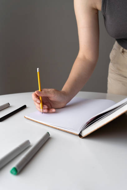 istock Hand holding a pencil ready to write on a blank page 2170177585