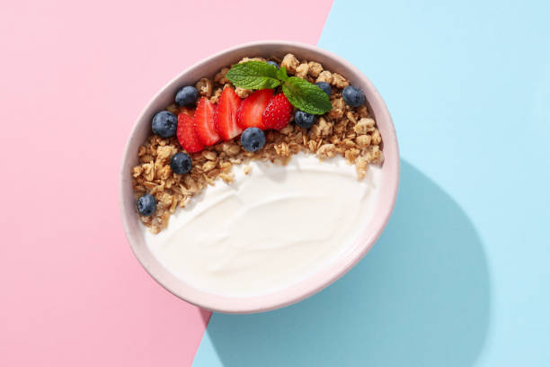 istock Bowl with yogurt and berries on pink and blue background, top view 2170184142