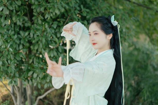 A Hanfu beauty playing outdoors by the lotus pond in summer