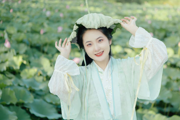 A Hanfu beauty playing outdoors by the lotus pond in summer