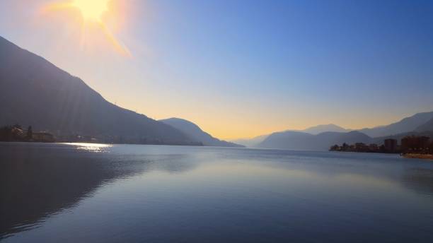 istock Sunny Day on Lake Como: Mountains, Yellow Sun, and Reflecting Water 2170193445