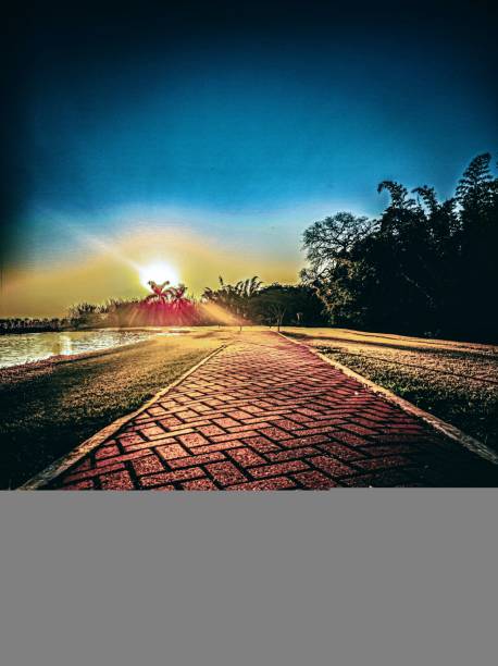 Golden Sun setting on the horizon, casting a warm glow across the sky and creating a mesmerizing reflection on the water. The sky is ablaze with vibrant hues of orange, yellow, and deep blue, creating a stunning backdrop for the serene landscap