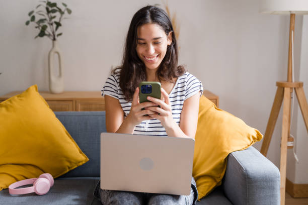 istock woman using smartphone while working on laptop at home 2170202797