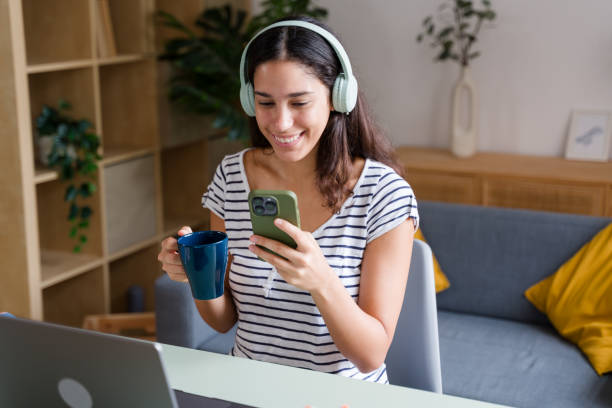 istock Happy freelancer woman using smartphone and drinking coffee at home office 2170203152
