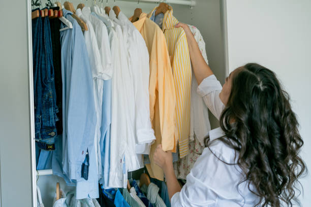 istock Young dark-haired curly beautiful woman is sorting things in large spacious closet. Home organization. Washing things. Analysis of clothes by season. 2170207734