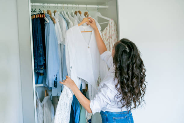 istock Young dark-haired curly beautiful woman is sorting things in large spacious closet. Home organization. Washing things. Analysis of clothes by season. 2170207763