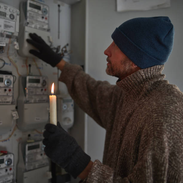 istock Checking the electricity power meter with a candle in cold winter days while there is power outage. 2170208820