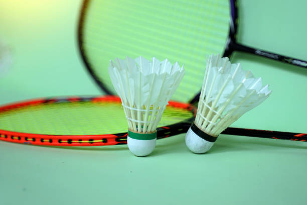 white shuttlecock on green background, blurred badminton racket and white shuttlecocks background. soft and selective focus.