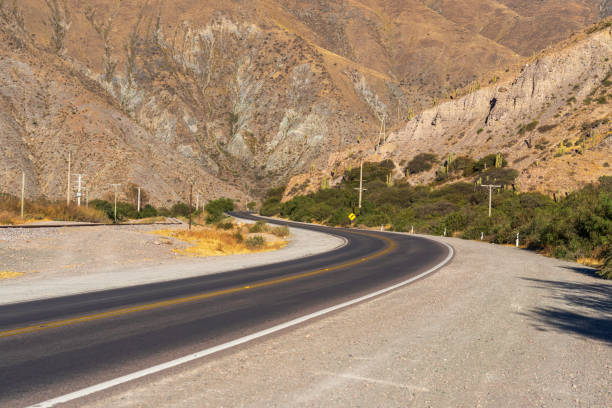 Asphalt road crossing dramatic dry landscape, Purmamarca, Jujuy, Argentina