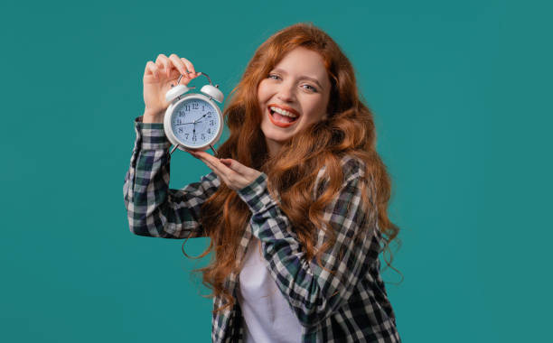 istock Happy red haired woman with alarm clock on blue background. Early morning, correct day routine, living in moment, appreciate every minute of life, youth. 2170214636