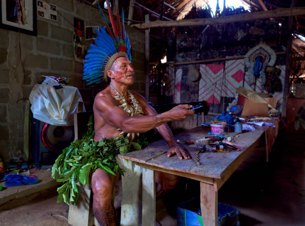 Close-up of an indigenous man from an Amazon tribe in Brazil changing television programs on his smart TV with his remote control