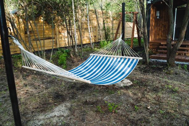 istock A tranquil setting features a blue and white striped hammock hanging in a yard, providing a peaceful spot for relaxation in a serene natural landscape with grass and shade 2170218588