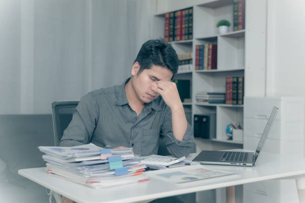 istock Young Asian man suffering from pain from working at desk, feeling tired from working on laptop and financial documents in office for a long time, Conceptual Office Syndrome 2170218936