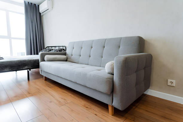 istock A grey couch is positioned in a living room next to a window, amidst subtle elements of furniture, building features, curtains, and wood providing a cozy and inviting atmosphere 2170219116