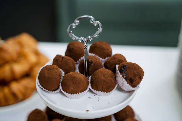 A white plate elegantly showcases chocolate truffles, a tempting dessert treat, creating a delightful presentation on the table for dessert lovers to enjoy the rich and indulgent flavors